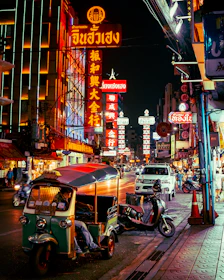 a street with neon signs and scooters