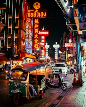 a street with neon signs and scooters