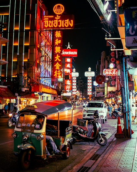 a street with neon signs and scooters