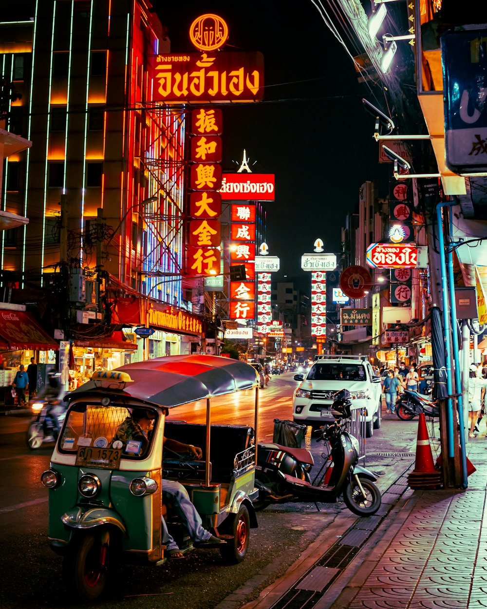 a street with neon signs and scooters