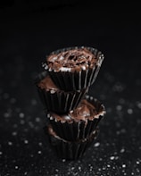 A stack of moist chocolate cupcakes with swirls of rich chocolate ganache and a sprinkle of sea salt.