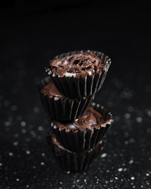 A stack of moist chocolate cupcakes with swirls of rich chocolate ganache and a sprinkle of sea salt.