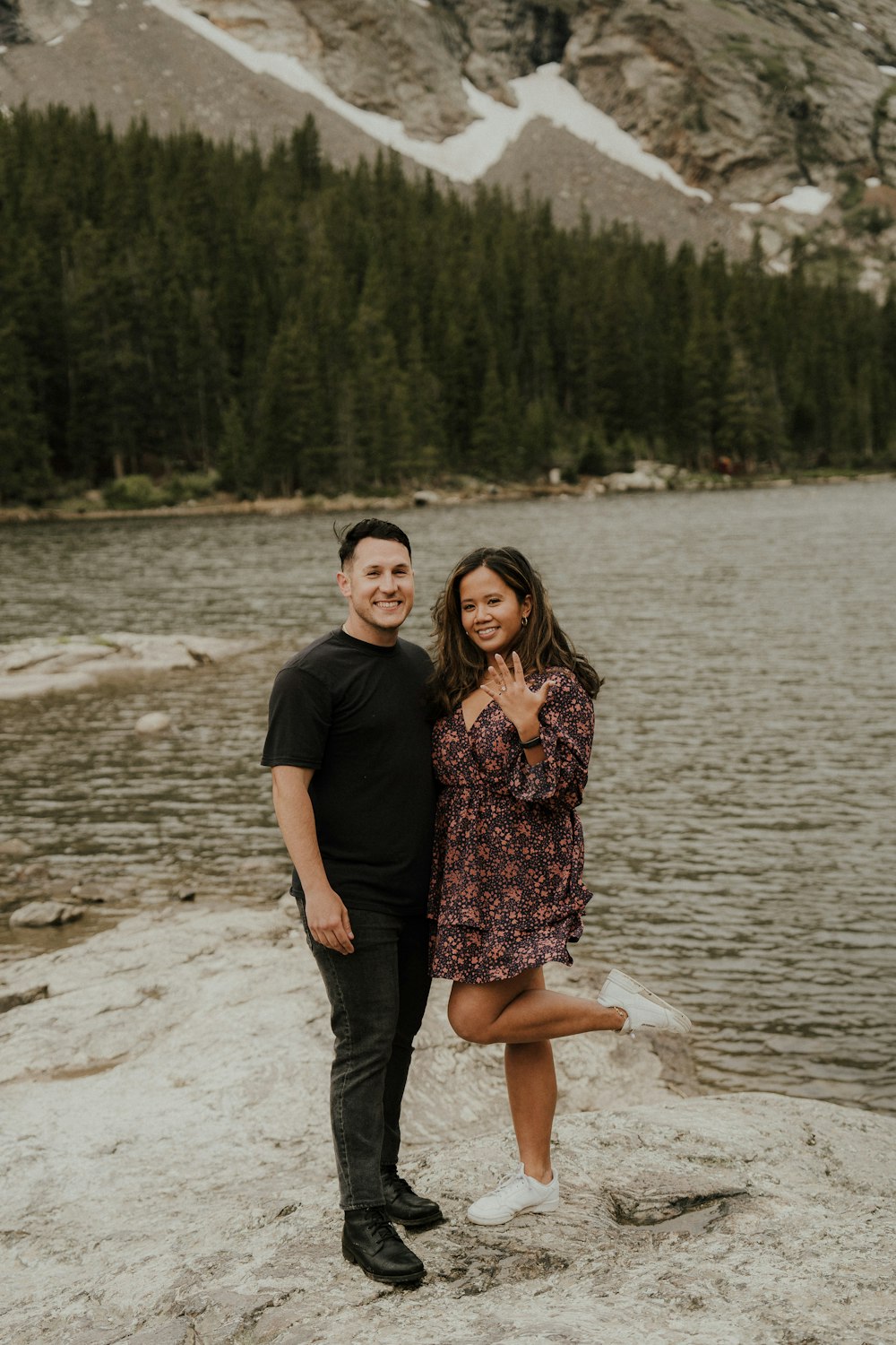 a man and woman posing for a picture next to a lake