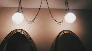 A pair of ornate wall sconces glowing gently beside a vintage mirror.