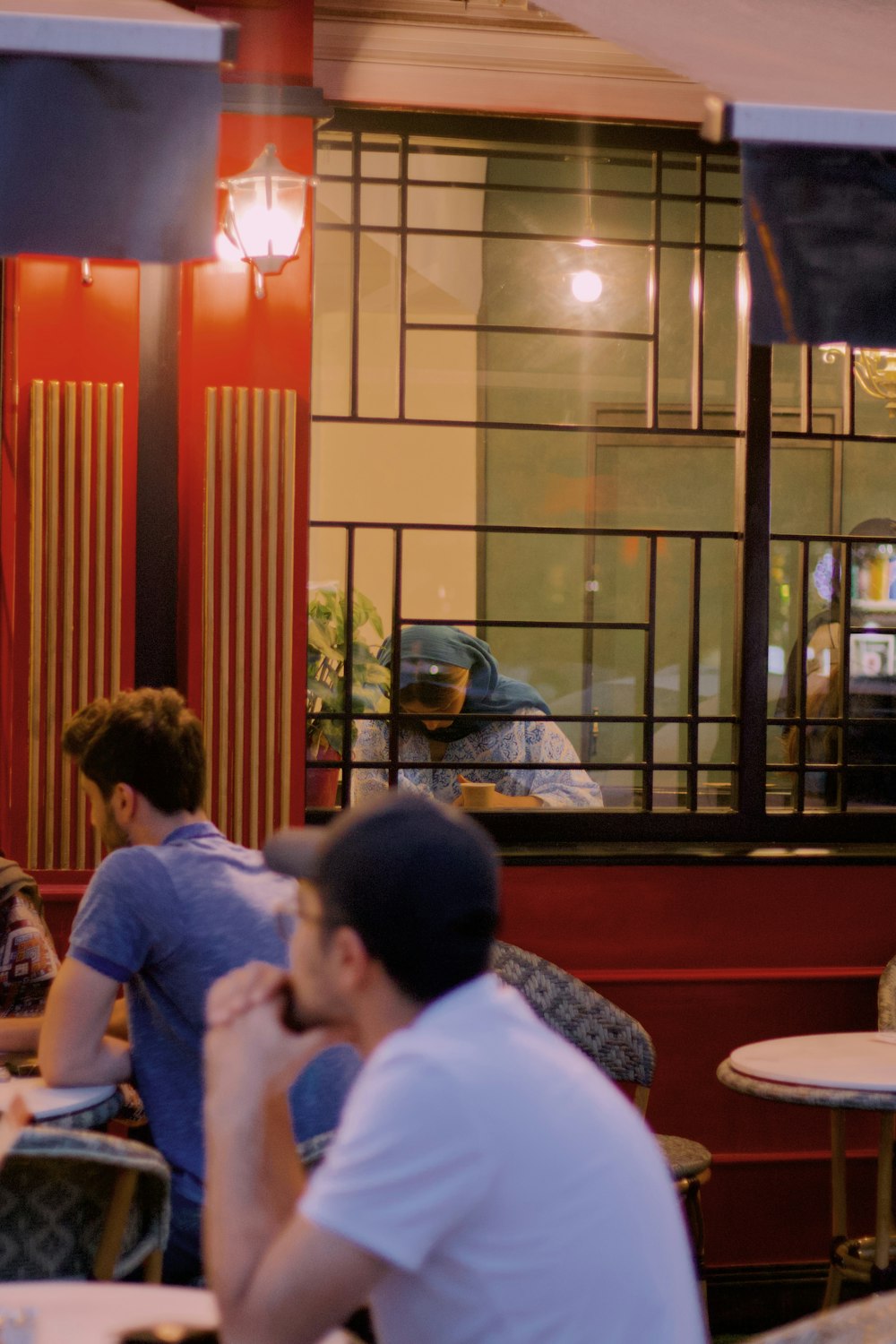 a couple of men sitting at a table looking at a window