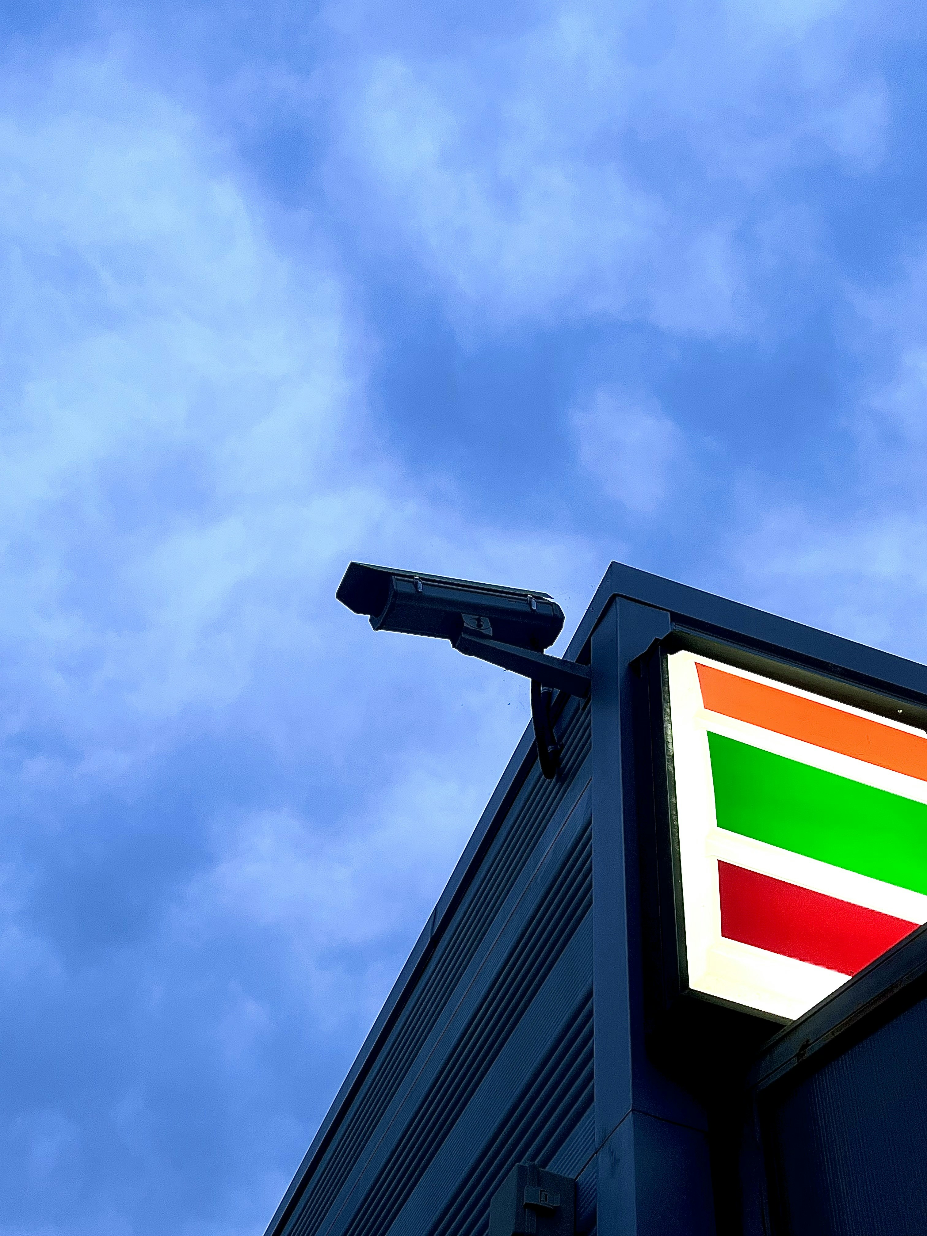 CCTV security camera installation on building exterior, night surveillance, dark dramatic sky, professional security equipment