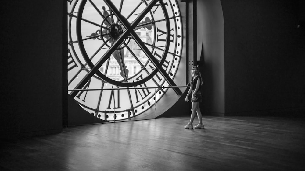 a person standing next to a large clock