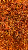 A dense collection of dried orange and red saffron strands intertwined in a textured pattern.