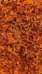 A dense collection of dried orange and red saffron strands intertwined in a textured pattern.