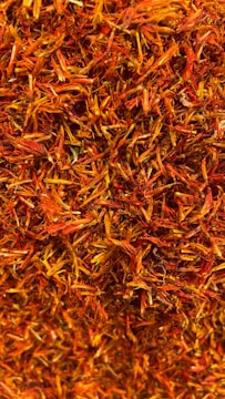 A dense collection of dried orange and red saffron strands intertwined in a textured pattern.