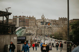a group of people walking on a street with buildings in the background