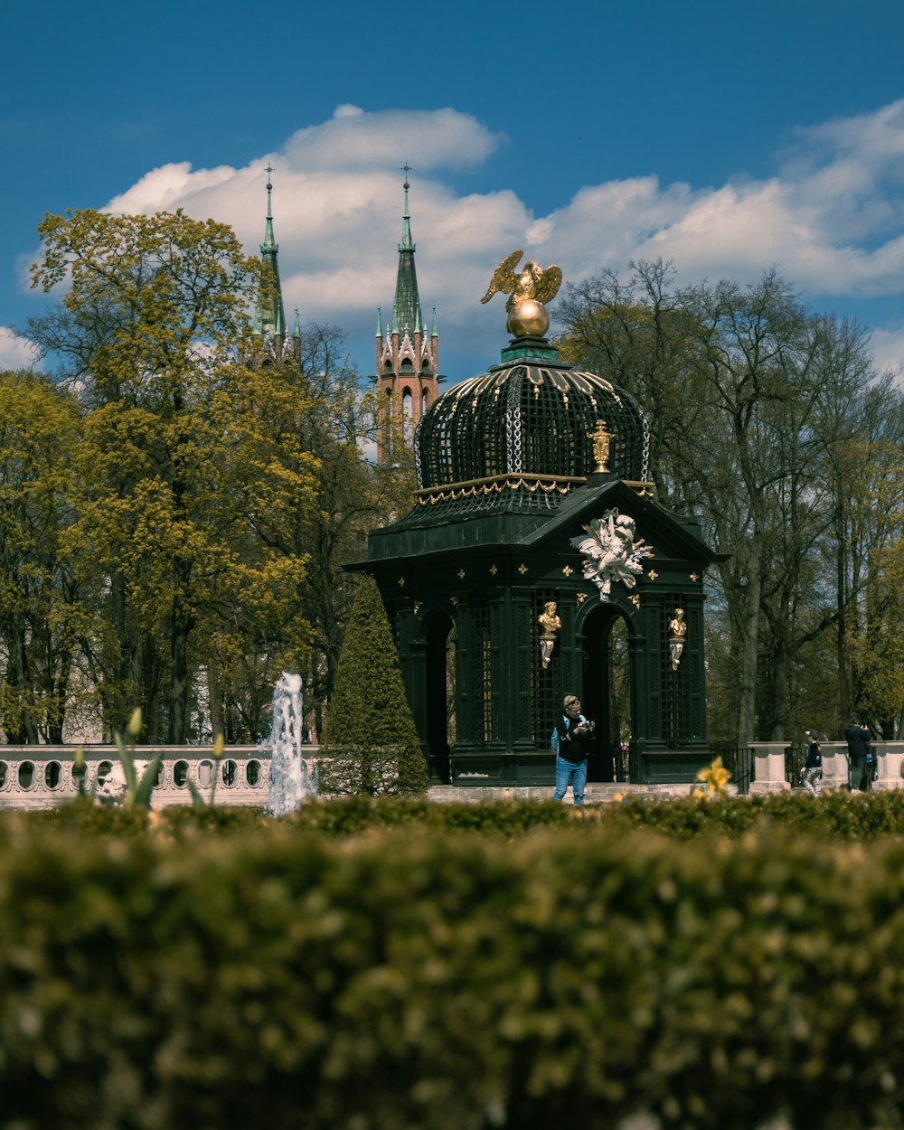 a person standing in front of a building with a gold statue on top