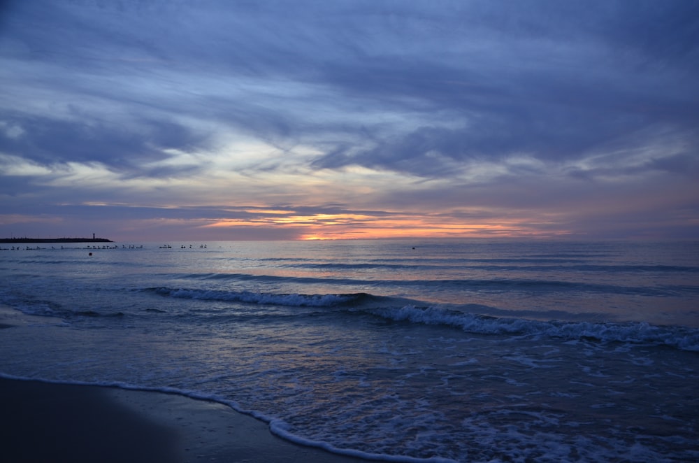 a beach with waves and a sunset