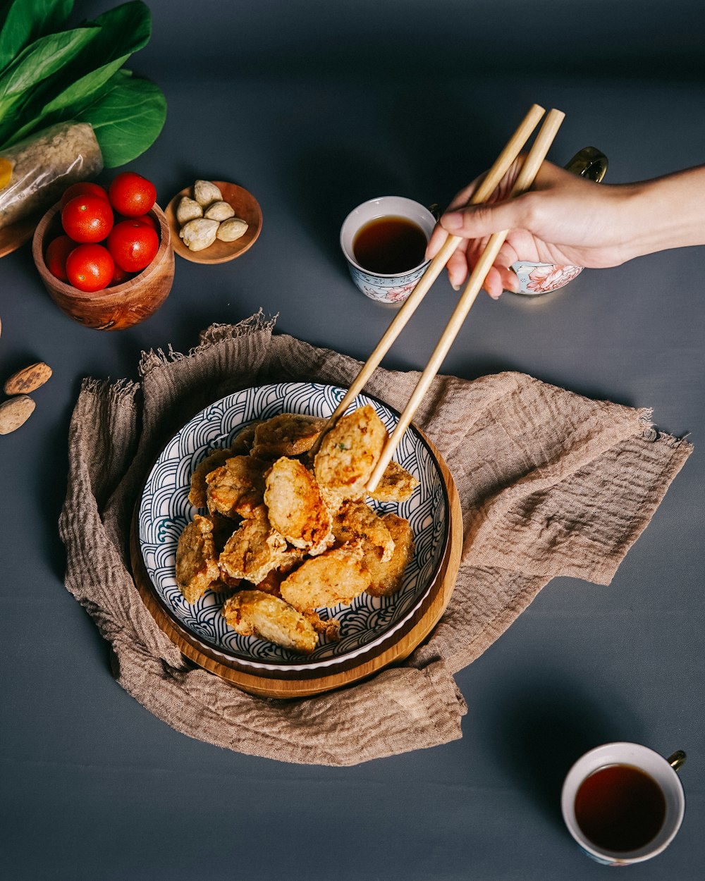 a person holding chopsticks over a plate of food