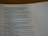 A close-up of an open book displaying a passage from the Bible. The text is printed in black ink on white paper, with some lines highlighted in bold. A dotted line is visible on the right side of the page.