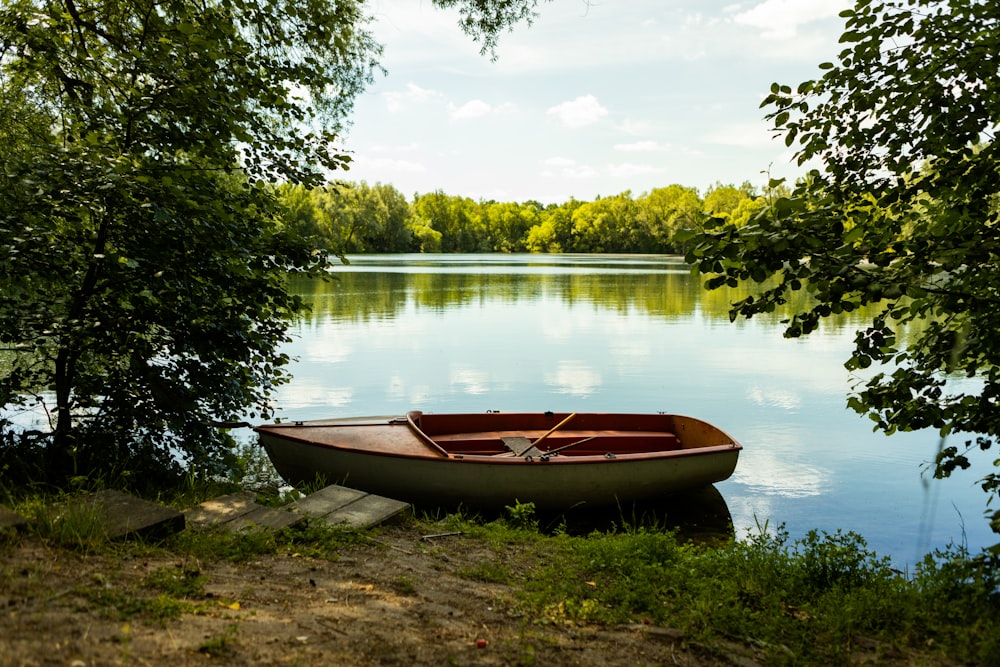 a boat sits on the shore of a lake