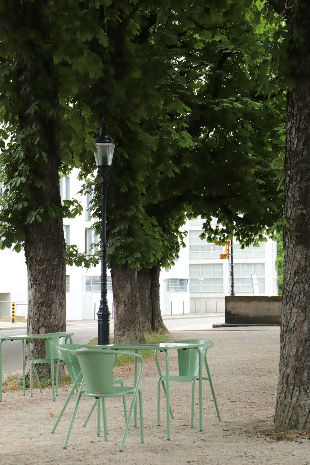 a group of green chairs and a lamp post on a sidewalk