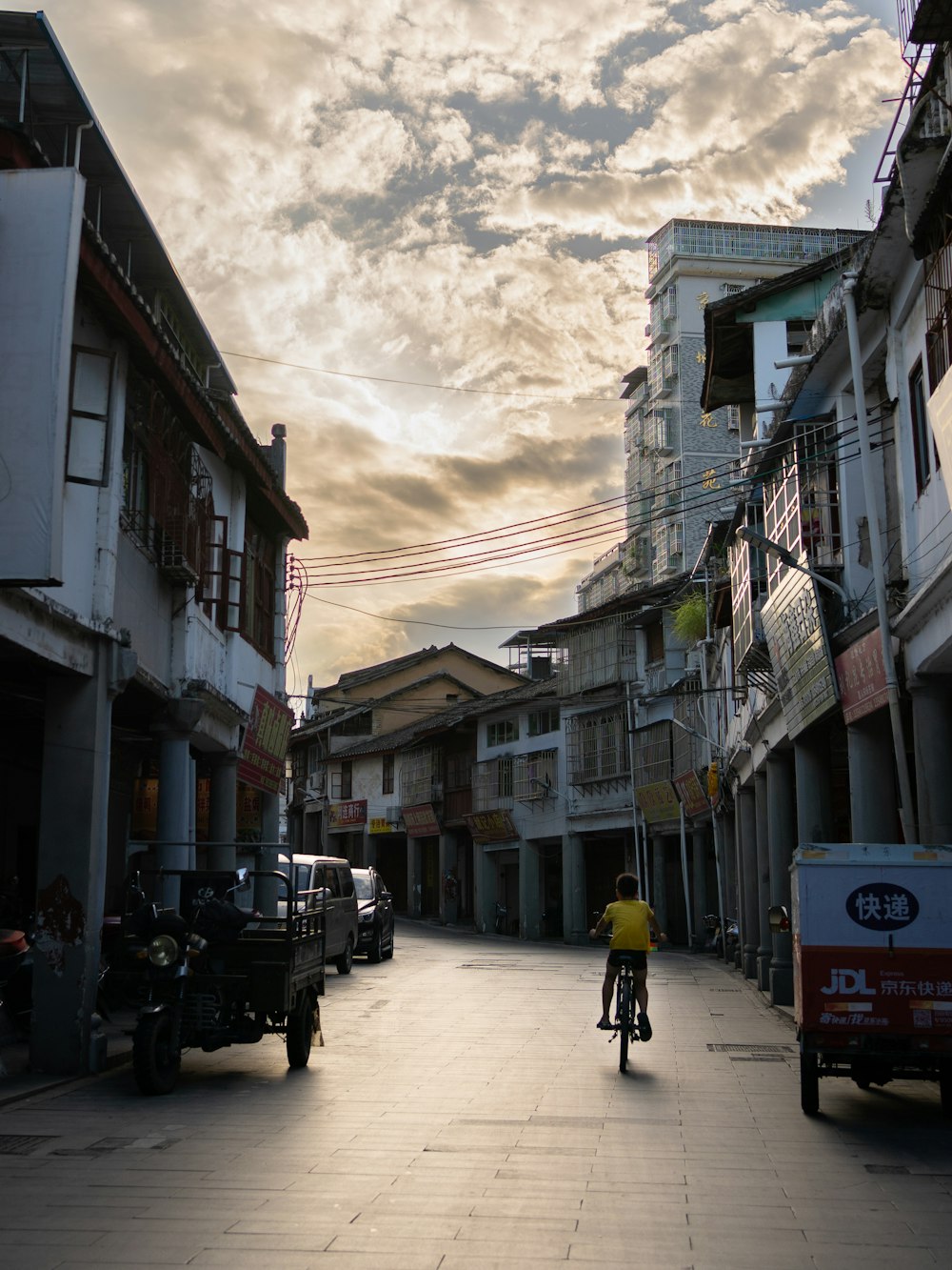 a person riding a bicycle on a street with buildings on either side