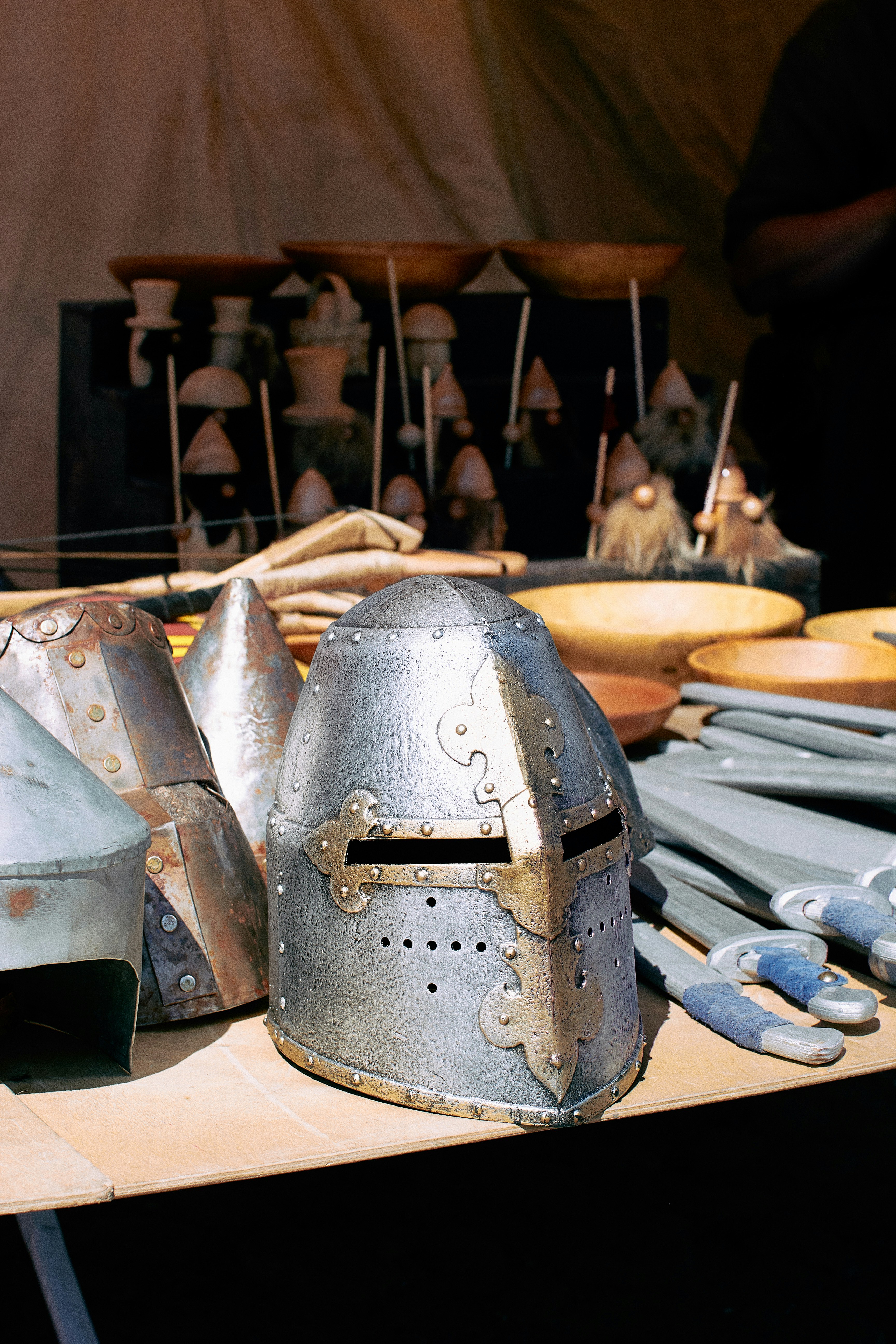 Medieval helmets and swords sit on a wooden display table.