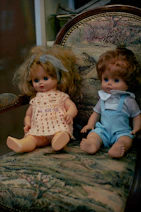 a couple dolls sitting on a chair