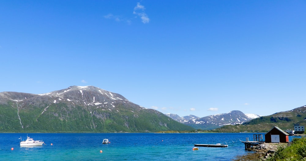 a body of water with boats and mountains in the background