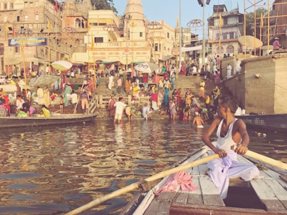a person rowing a boat in a canal with people on the side