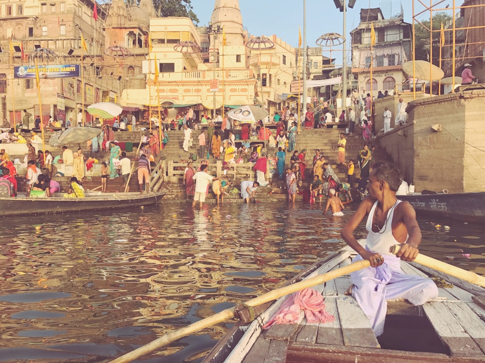 a person rowing a boat in a canal with people on the side