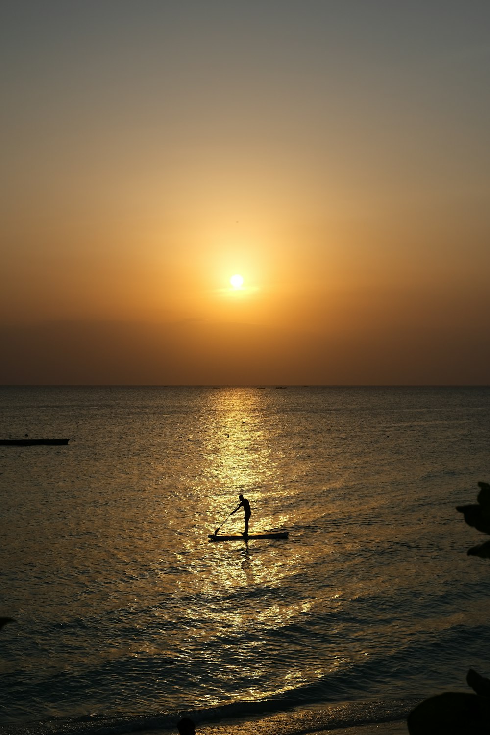 a person on a surfboard in the water with the sun setting