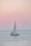 A serene sailboat gliding through calm Venetian lagoon waters at sunset.
