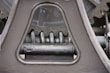Close-up view of a mechanical gear system, featuring large metal components with visible gears and axles. The metal surfaces are painted in a matte gray color, with signs of wear and some accumulated grease at the joints.