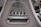 Close-up view of a mechanical gear system, featuring large metal components with visible gears and axles. The metal surfaces are painted in a matte gray color, with signs of wear and some accumulated grease at the joints.