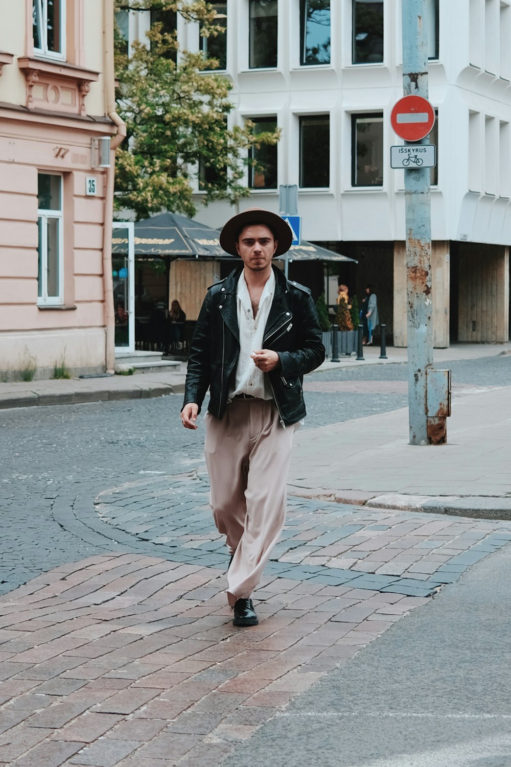 a man wearing a hat and walking on a street