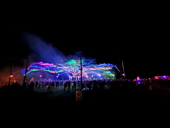 A vibrant crowd dancing under colorful lights at a nocturna event.