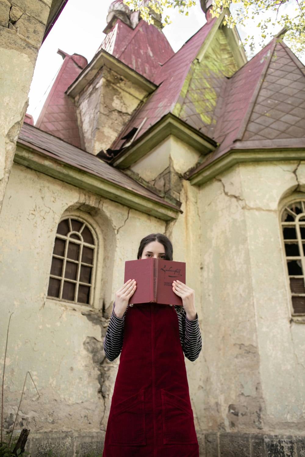 a person in a red dress holding a book in front of a building