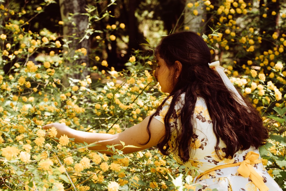 a woman in a yellow dress lying in a field of flowers