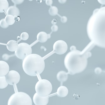 A 3D illustration of interconnected white spheres resembling molecular structures set against a soft, blurred backdrop. The spheres are depicted in various sizes, connected by straight rods, creating an impression of a complex network or chemical compound.