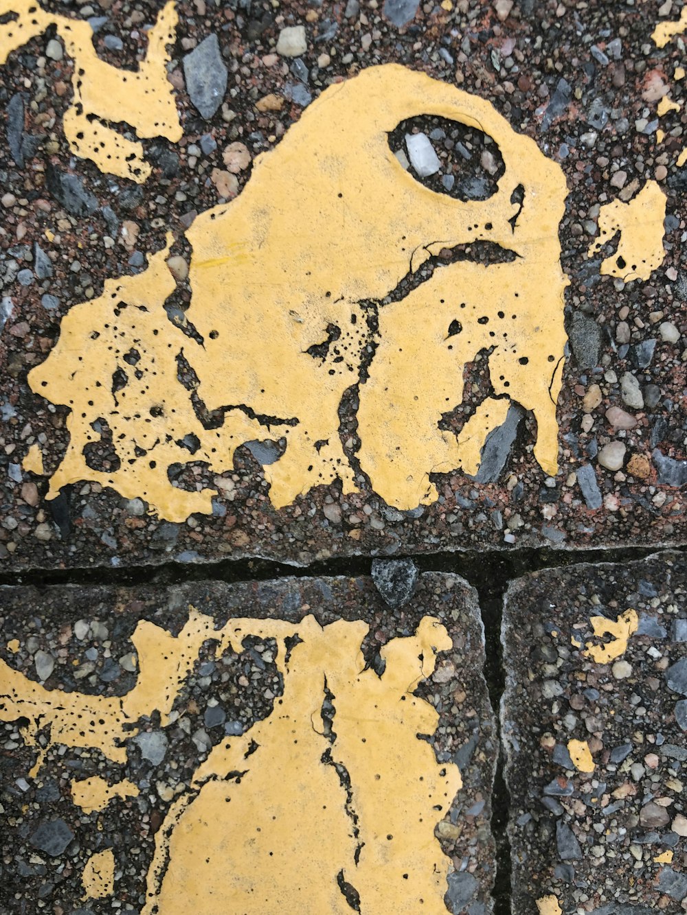 a yellow painted face on a rock