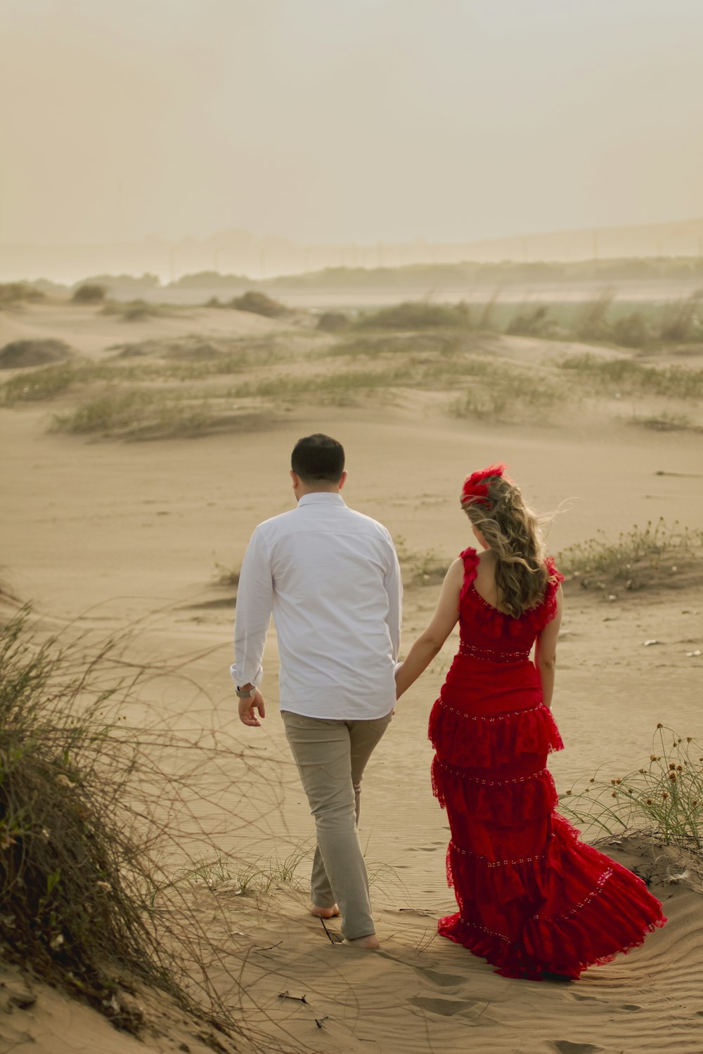 a man and woman walking on a sandy beach