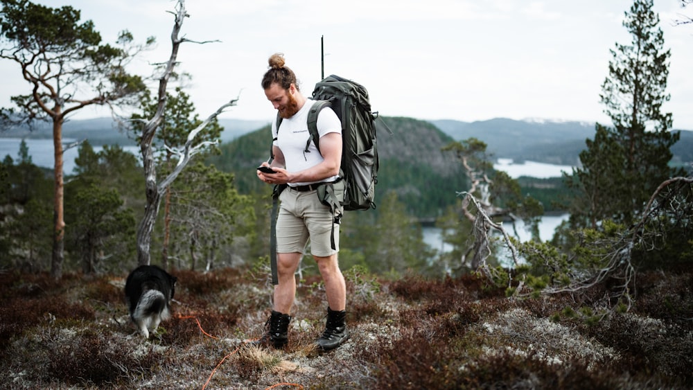 a person with a backpack and a dog on a trail by a lake