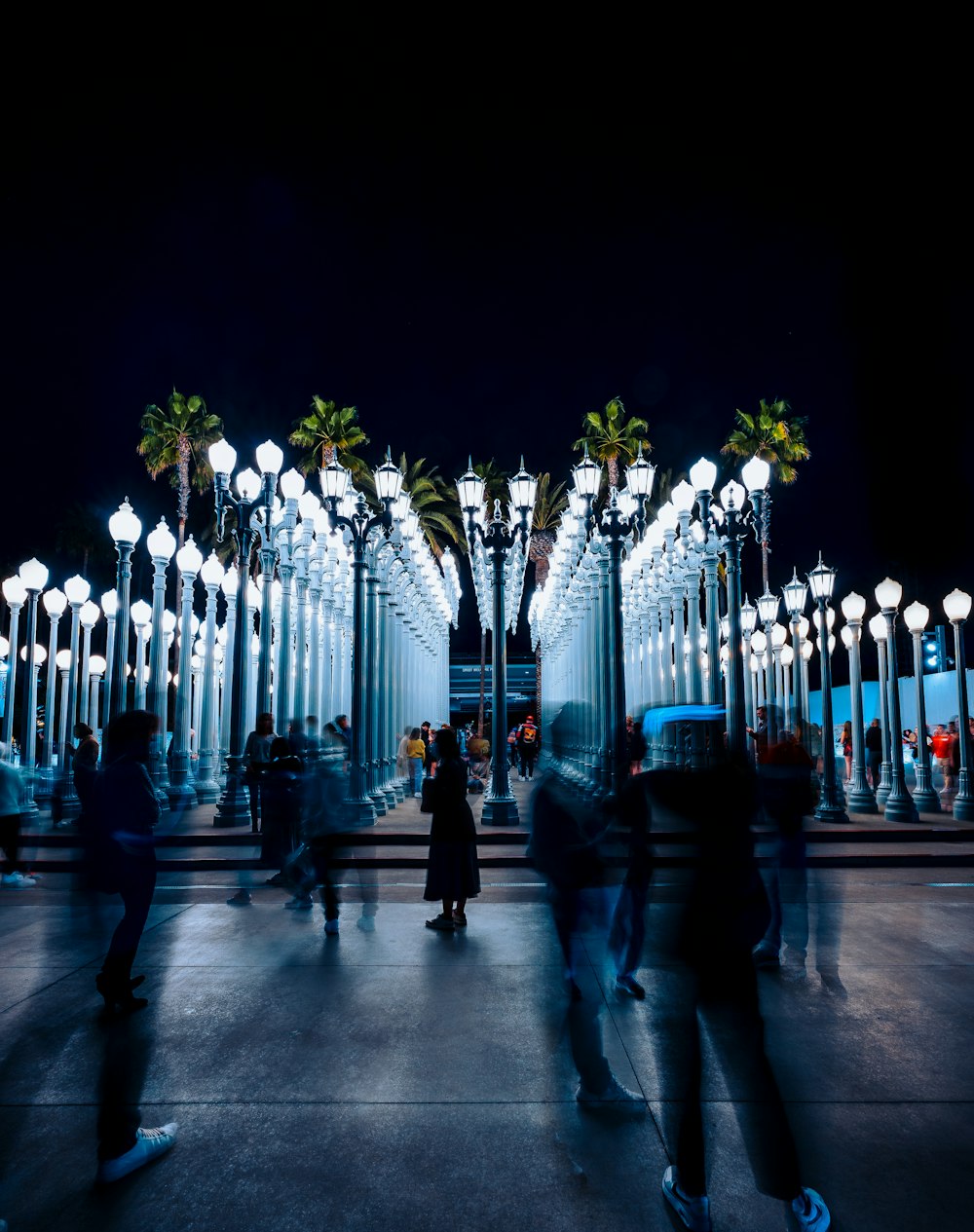 a group of people walking on a sidewalk with lights