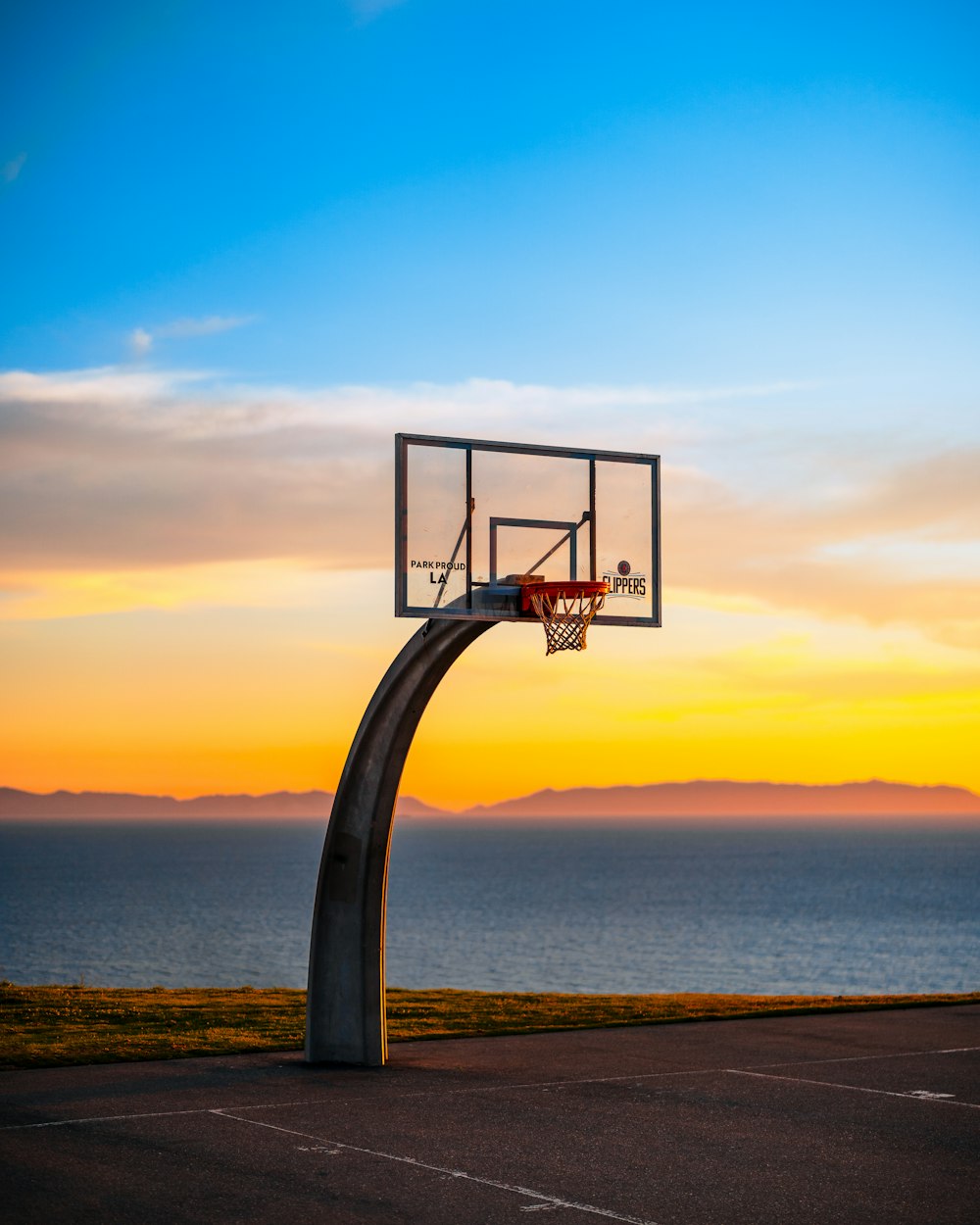 a basketball hoop on a road by the water