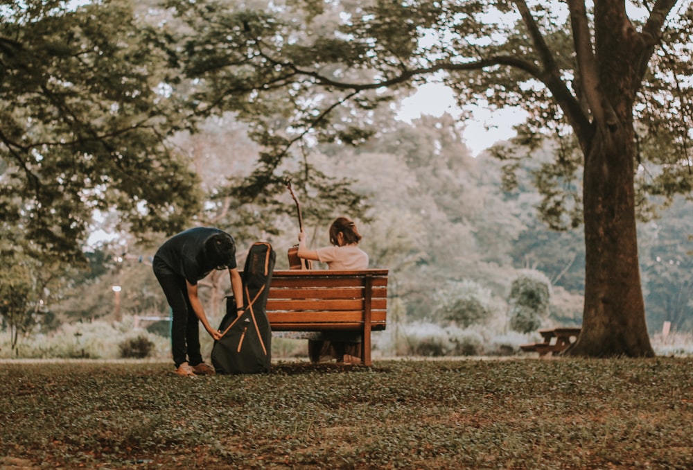 a man and woman sitting on a bench in a park