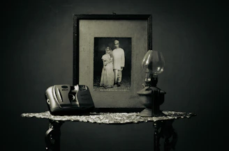 A minimalist setup with vintage camera and wedding rings on a wooden table, evoking nostalgia.