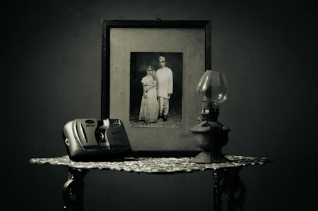 A minimalist setup with vintage camera and wedding rings on a wooden table, evoking nostalgia.