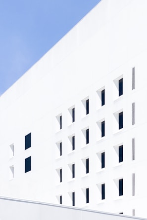 Minimalist modern building facade with clean white surfaces and sharp lines under natural light.