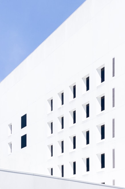 Exterior building facade painted bright white under clear blue sky