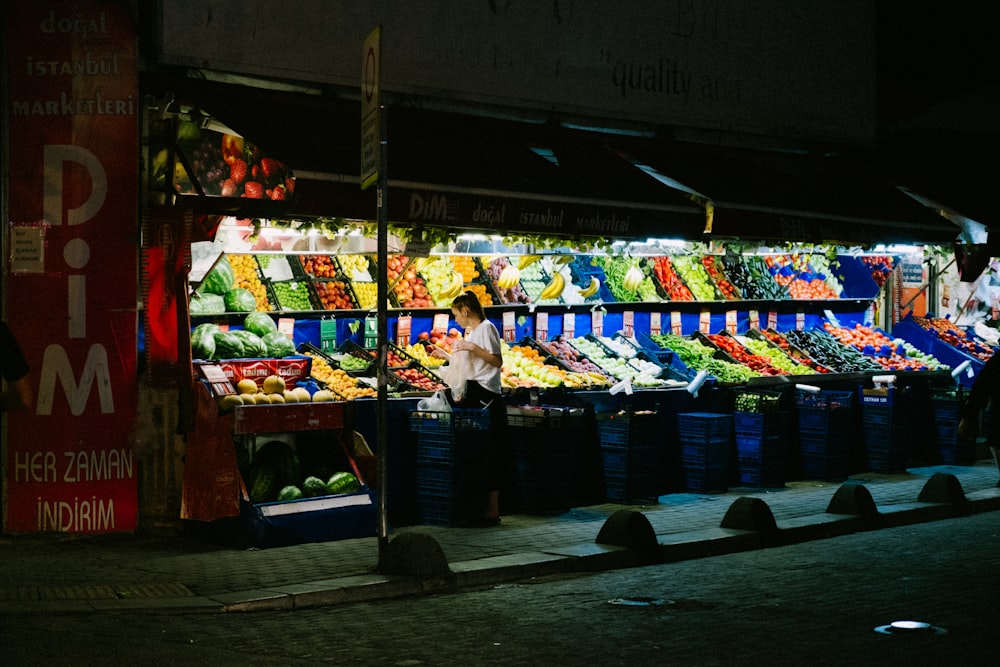 a person standing in front of a fruit stand