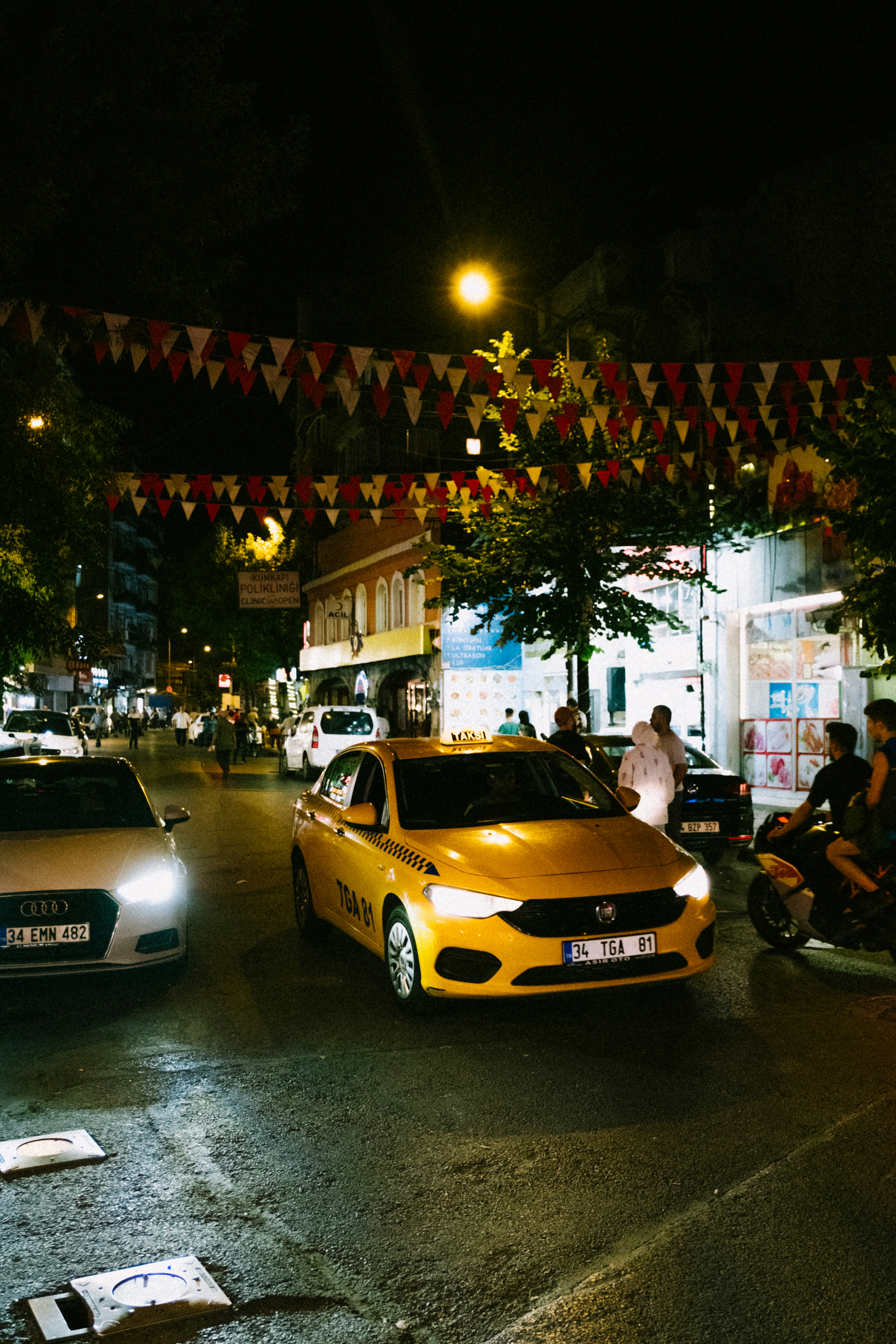 a yellow car parked on the side of a street with a building with lights