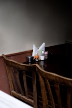 Close-up of wooden table drawers holding cutlery, napkins, salt, and pepper in a warm brown-toned dining area.