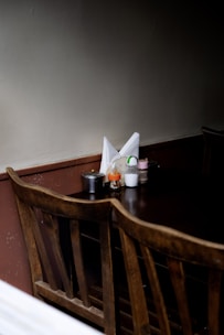 Close-up of wooden table drawers holding cutlery, napkins, salt, and pepper in a warm brown-toned dining area.
